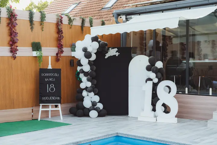 Dekoracija za 18. rođendan sa crno-belim balonima pored bazena