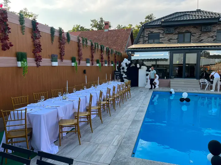 Dugi sto sa zlatnim chiavari stolicama pored bazena