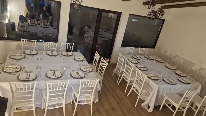 Postavljeni stolovi sa belim chiavari stolicama u restoranu